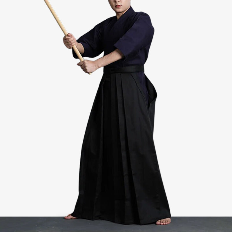 Un homme en tenue d'art martial japonais tient dans la main un katana en bois