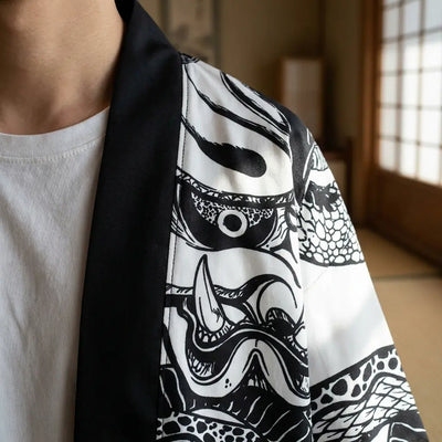 Gros plan sur le tissu imprimé du haori, les traits d'encre du masque ressortant sur fond blanc