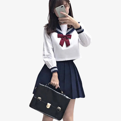 Uniforme japonais marin inspiré du sailor fuku, porté par les étudiantes japonaises, avec une chemise blanche, une jupe plissée et un ruban.