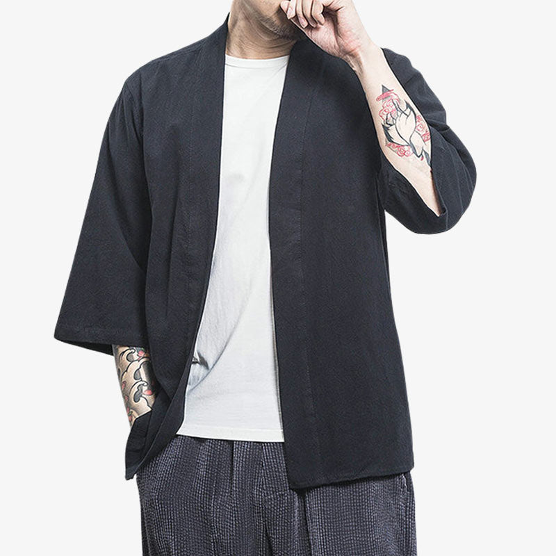 Un homme est vêtu d'une veste kimono japonais cardigan de couleur noire. La matière est en lin et en coton. C'est un vêtement japonais uni