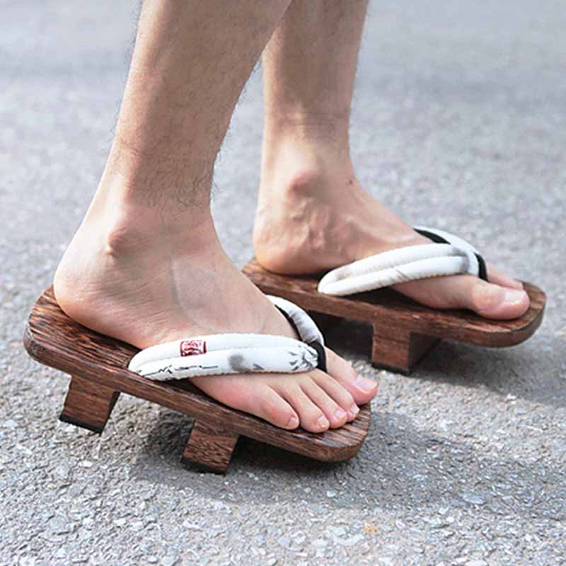 Un homme porte aux pieds des chaussures traditionnelles japonaises. Ce sont des sandales en bois