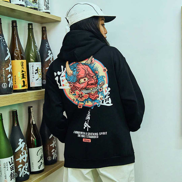 Un femme porte un hoodie demon japon et une casquette blanche