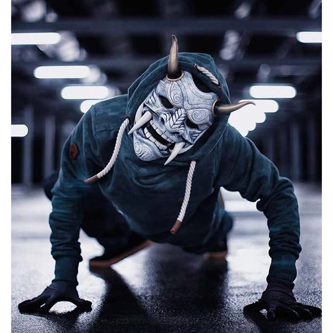 Un homme porte un masque japonais Hanny blanc demon avec un hoodie à capuche