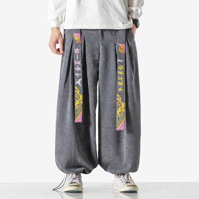 Un homme porte un pantalon sarouel japonais avec un t-shirt blanc et des chaussures sneakers blanches