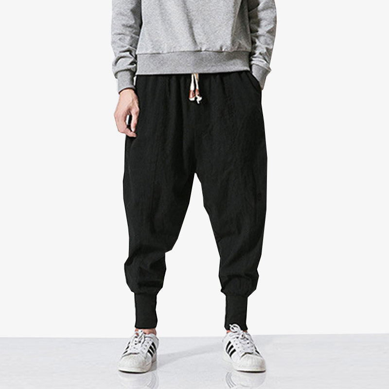 Un japonais porte un pantalon streetwear homme avec des baskets sneakers blanches et un pull manches longues de couleur gris