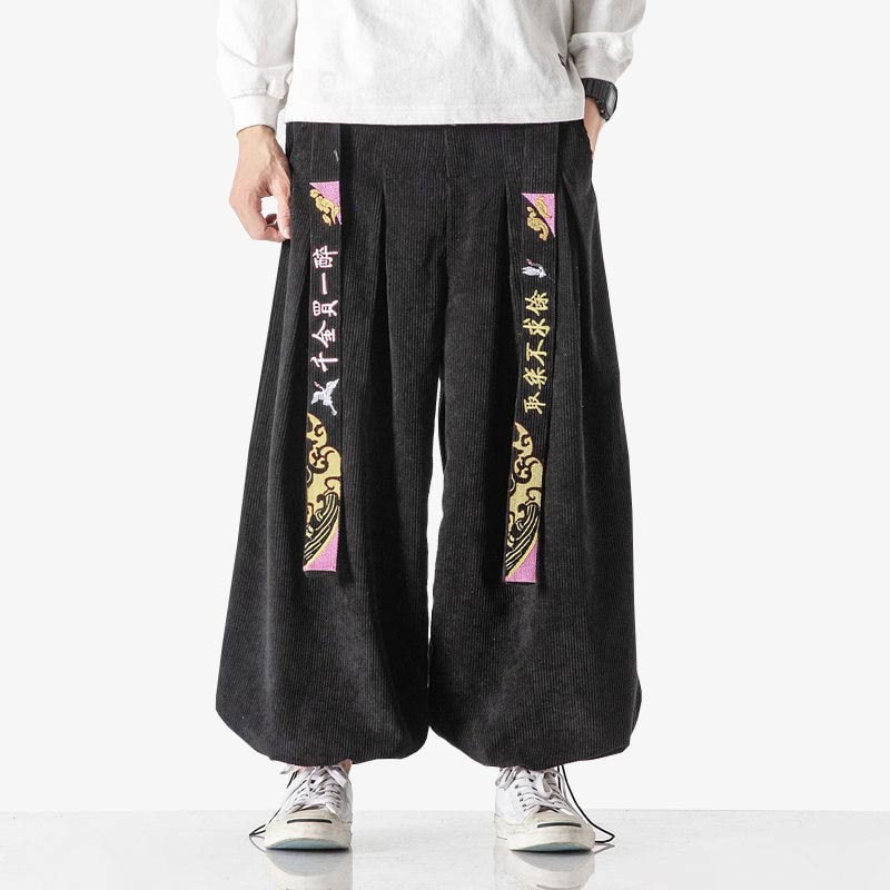 Un homme porte un sarouel japonais avec une ceinture motifs kanji. Il porte aux pieds des sneakers blanches ainsi qu'un t-shirt oversize blanc