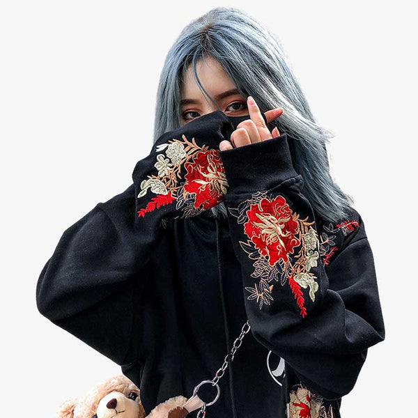 Une femme porte un sweat a capuche motif japonais de couleur noir avec des motifs brodés sur les manches en coton