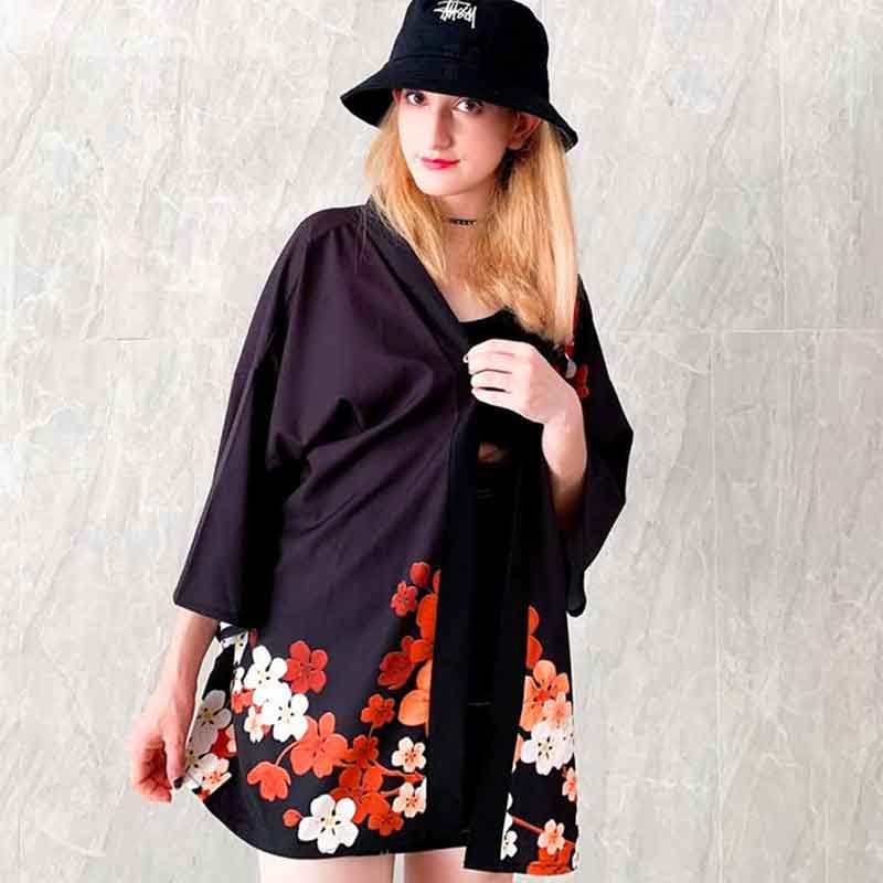 Une femme blonde porte une veste de kimono japonais avec un motif sakura rouge et blanc