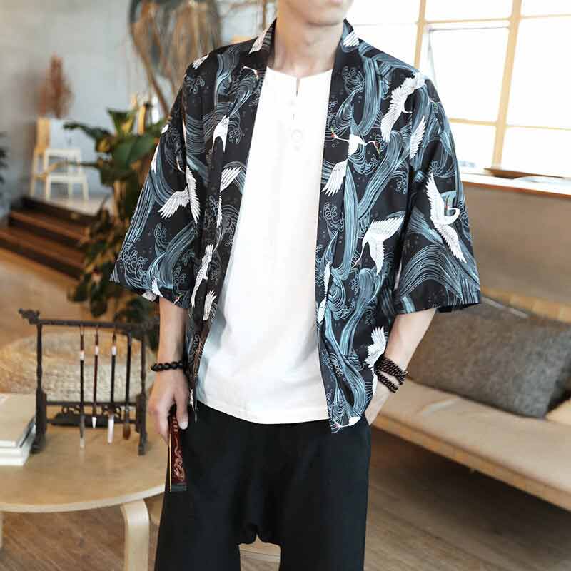 Une veste homme style kimono imprimée avec des oiseaux blancs. L'homme porte un T-shirt blanc et un pantalon noir cargo