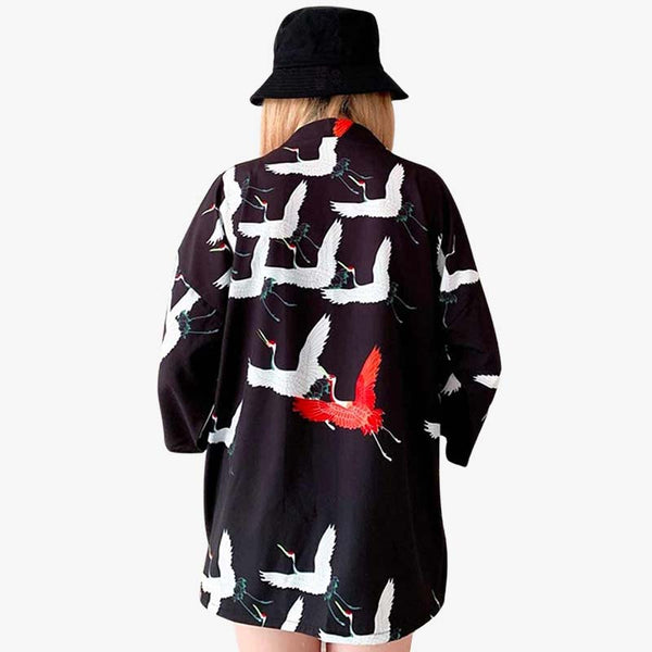 Une femme porte une veste kimono noir avec des motifs d'oiseaux japonais